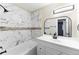 Bathroom featuring a white vanity, tub with marble-style tile surround, and modern black fixtures at 3608 W Radcliff Ave, Denver, CO 80236