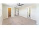 A large bedroom featuring carpet floors, a ceiling fan, three white doors, and light-colored walls at 3608 W Radcliff Ave, Denver, CO 80236