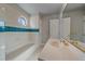 Bathroom featuring a tiled tub with a blue accent stripe, vanity, and octagonal window at 8225 S Cody St, Littleton, CO 80128