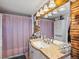 Bathroom with wood paneling, unique vanity with a mirror and a shower with pink curtains at 402 Harrison Ave, Fort Lupton, CO 80621