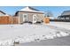 View of the home's exterior in the winter, showcasing the yard, sidewalk and gray siding at 402 Harrison Ave, Fort Lupton, CO 80621