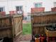 Backyard featuring a wooden fence with an open gate, small patio, potted flowers, and adjacent building at 17664 E Loyola Dr # C, Aurora, CO 80013
