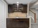 Finished basement bar area with sink, granite countertops, dark wood cabinets, and a wine rack at 17223 W 84Th Dr, Arvada, CO 80007