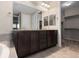 Bathroom featuring dual sink vanity with dark cabinets and walk-in closet access at 17223 W 84Th Dr, Arvada, CO 80007