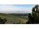 Scenic view overlooking green hills with the silhouette of a distant city skyline on a sunny day at 17223 W 84Th Dr, Arvada, CO 80007