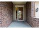 Close-up of a brick-lined front porch with a secure metal security door and natural light window at 17223 W 84Th Dr, Arvada, CO 80007
