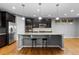 Open-concept kitchen featuring hardwood floors, center island with bar seating, and stainless steel appliances at 17223 W 84Th Dr, Arvada, CO 80007
