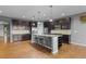 Open kitchen featuring an island with granite countertops, dark wood cabinets, stainless appliances, and hardwood flooring at 17223 W 84Th Dr, Arvada, CO 80007