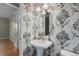 Stylish powder room with patterned wallpaper, pedestal sink, and elegant lighting at 17223 W 84Th Dr, Arvada, CO 80007