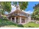 Spacious back exterior featuring a brick facade, covered deck, and beautifully landscaped yard at 7769 W 70Th Dr, Arvada, CO 80004