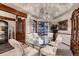Sunlit dining room with modern chandelier, large windows, ceiling detail, and a glass-topped dining table at 7769 W 70Th Dr, Arvada, CO 80004
