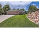 Lovely brick home boasts mature trees, a well-manicured lawn, and lush landscaping at 7769 W 70Th Dr, Arvada, CO 80004