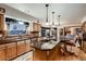 Open kitchen featuring wood cabinets, a center island with a cooktop, stainless appliances, and tile backsplash at 7769 W 70Th Dr, Arvada, CO 80004