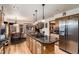 Spacious kitchen with stainless steel refrigerator, hardwood floors, and large center island with range and seating at 7769 W 70Th Dr, Arvada, CO 80004
