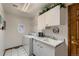 Well-lit laundry room featuring a washer, dryer, sink, storage cabinets, and a round window at 7769 W 70Th Dr, Arvada, CO 80004