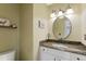Powder room featuring a vanity with granite countertop, decorative mirror, sconce lighting, and a toilet at 12 Long Spur, Littleton, CO 80127