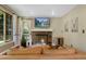 Cozy living room featuring a brick fireplace, comfortable leather sofa, and natural light from large windows at 12 Long Spur, Littleton, CO 80127