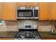 Modern kitchen featuring stainless steel appliances, granite countertops, and tiled backsplash at 16815 E Prairie Goat Ave, Parker, CO 80134