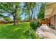 Lush backyard featuring a manicured lawn, mature trees, and a privacy fence at 7427 W Cedar Cir, Lakewood, CO 80226