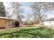 Picturesque backyard with lush green grass, mature trees, and a partially covered patio area at 6580 Independence Way, Arvada, CO 80004