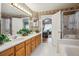 Bright bathroom featuring a double sink vanity, shower, and soaking tub with decoratively tiled wall at 17038 Lamar Dr, Parker, CO 80134