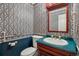 Cozy half bathroom with blue, red and white wallpaper, a wooden trimmed mirror and green countertops at 17038 Lamar Dr, Parker, CO 80134