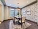 Inviting dining room featuring an elegant light fixture, brick accent wall, and large windows at 1648 Exquisite St, Castle Rock, CO 80109