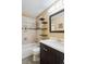Well-lit bathroom showcases a tub with tiled walls, black shelving, and a vanity with a white countertop at 19113 W 60Th Ln, Golden, CO 80403