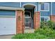 Welcoming front entrance with brick columns, an ornate storm door, and lush landscaping at 19113 W 60Th Ln, Golden, CO 80403