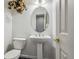 Compact powder room featuring a pedestal sink, decorative mirror and tiled flooring at 17391 E Weaver Ave, Aurora, CO 80016