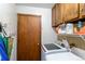Bright laundry room with modern appliances, wooden cabinets, and storage shelves at 750 S Dearborn Ct, Aurora, CO 80012