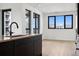 Modern kitchen featuring dark cabinets, a large center island and hardwood floors with views from every window at 1601 Park Ave # 506, Denver, CO 80218