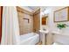 Cozy bathroom with tiled walls, a pedestal sink, bathtub with shower, and decorative accents at 3246 S Stuart St, Denver, CO 80236