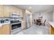 Open kitchen and dining area with stainless steel appliances, wooden table and gray tile flooring at 3246 S Stuart St, Denver, CO 80236