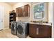 Well-equipped laundry room with modern washer and dryer, storage cabinets, and a utility sink at 5091 Hidden Pond Pl, Castle Rock, CO 80108
