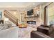 Cozy living room featuring a stone fireplace, staircase, and comfortable seating at 5091 Hidden Pond Pl, Castle Rock, CO 80108