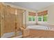 Bathroom featuring a glass shower, soaking tub, and natural light from two windows at 6533 S Ouray St, Aurora, CO 80016