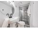 Stylish bathroom featuring a round mirror, modern lighting, and a glass-enclosed shower with decorative tile accents at 3249 W Alaska Pl, Denver, CO 80219