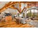 Open floor plan living room with exposed wood beams, expansive windows, stone fireplace, and hardwood flooring at 174 Sage Dr, Breckenridge, CO 80424