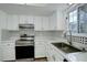 Bright kitchen featuring white cabinetry, stainless steel appliances, and stylish black and white backsplash at 2466 S Vaughn Way # A, Aurora, CO 80014