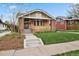 Charming brick home featuring a covered front porch, well-maintained lawn, and beautiful architectural details at 916 Adams St, Denver, CO 80206