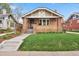 Charming brick home featuring a covered front porch, well-maintained lawn, and beautiful architectural details at 916 Adams St, Denver, CO 80206