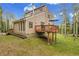 Multi-level home boasts a deck with a wooden railing, surrounded by mature trees on a sunny day at 2654 Sinton Rd, Evergreen, CO 80439