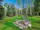 Outdoor fire pit surrounded by chairs, lush green lawn and mature aspen trees on a sunny day at 2654 Sinton Rd, Evergreen, CO 80439