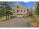 Two-story house with a two-car garage, balcony, stone accents, and a paved driveway, surrounded by a natural landscape at 2654 Sinton Rd, Evergreen, CO 80439