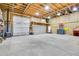 Spacious, unfinished garage with a high ceiling, exposed wood beams, two large bay doors and ample lighting at 2654 Sinton Rd, Evergreen, CO 80439
