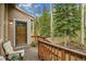 Inviting covered front porch with wood railings, cozy seating, a beautiful wooden door and scenic views at 2654 Sinton Rd, Evergreen, CO 80439