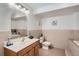 Retro tiled bathroom has tile flooring, tub access, updated light fixtures, and an oval mirror at 2417 S Racine Way, Aurora, CO 80014