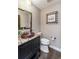 Charming powder room with dark vanity, granite countertops, and a unique, colorful mirror at 2601 S Quebec St # 6, Denver, CO 80231