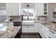 Bright kitchen featuring a farmhouse sink, granite countertops, white cabinets, and stainless steel appliances at 2601 S Quebec St # 6, Denver, CO 80231